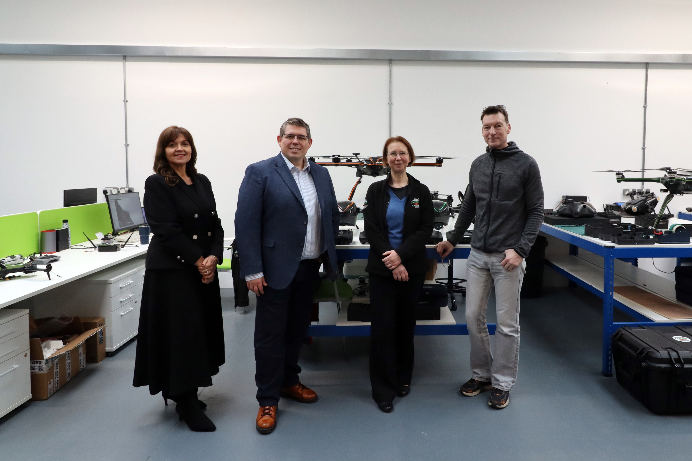 Two men and two women stood in front of large drones